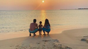 A sunset over a beach with a family of three. - Exclusive apartment in Lecherías 1 min walk to the beach (Lechería)