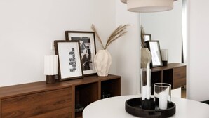 A modern interior with a wooden console, framed pictures, a vase, and a mirror.