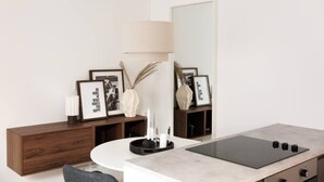 A modern kitchen with a round island, a wooden cabinet, and framed pictures on the wall.