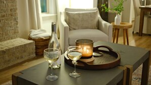 A cozy living room with a wooden table, two wine glasses, a candle, and a bottle. - Plainsman Retreat-4min to AU, Gameroom,Pickleball+ (Auburn)