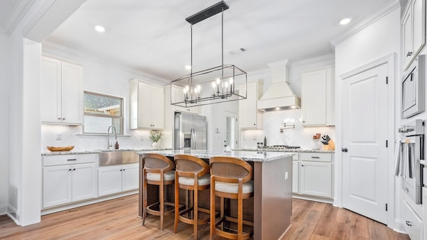 A modern kitchen with white cabinetry, a central island with bar stools, stainless steel appliances, and a pendant light. - Plainsman Retreat-4min to AU, Gameroom,Pickleball+ (Auburn)