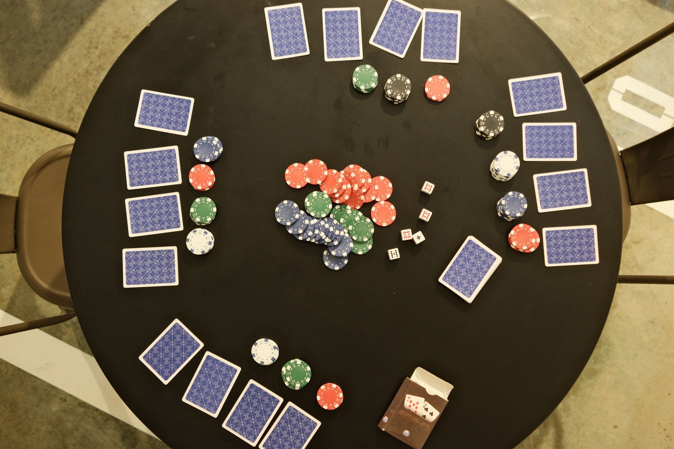 A circular table with poker chips and playing cards arranged on it.