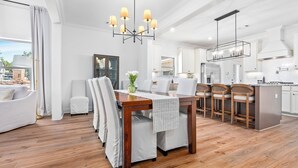 A modern kitchen with white cabinets, a wooden dining table, and bar stools. - Plainsman Retreat-4min to AU, Gameroom,Pickleball+ (Auburn)