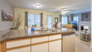 Une cuisine moderne dotée de plans de travail en granit, d’un lave-vaisselle et d’un coin repas avec une table et des chaises.