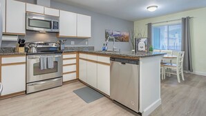 Een moderne keuken met roestvrijstalen apparatuur, witte kastjes en een geïntegreerde vaatwasser.