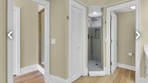A hallway with beige walls and white trim, leading to a room with a shower. - Naples Florida - This condo is like no other!! Windstar on Naples's Bay (Naples)