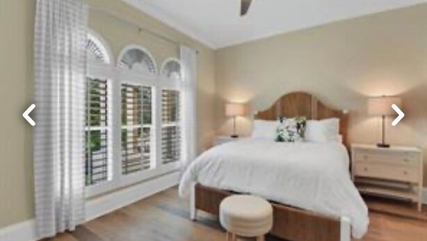 A bedroom with a large bed, bedside tables, a nightstand, and a window with curtains. - Naples Florida - This condo is like no other!! Windstar on Naples's Bay (Naples)