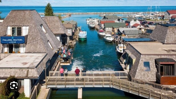A marina with boats docked, a wooden bridge, and a building labeled "Falling Waters Lodge". - Whaleback Retreat (Leland)
