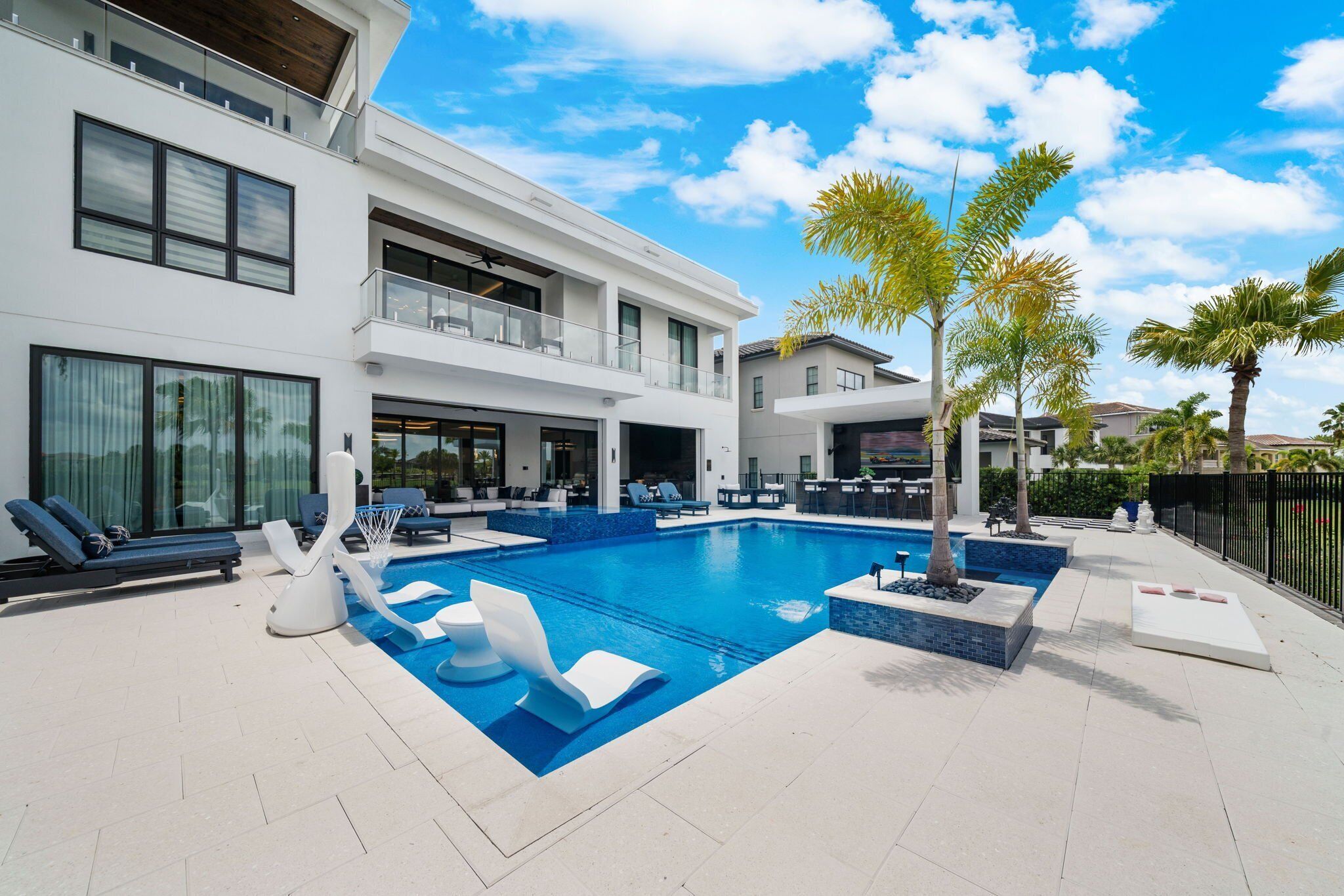 A modern pool area with lounge chairs, a pool, and a two-story building with balconies.