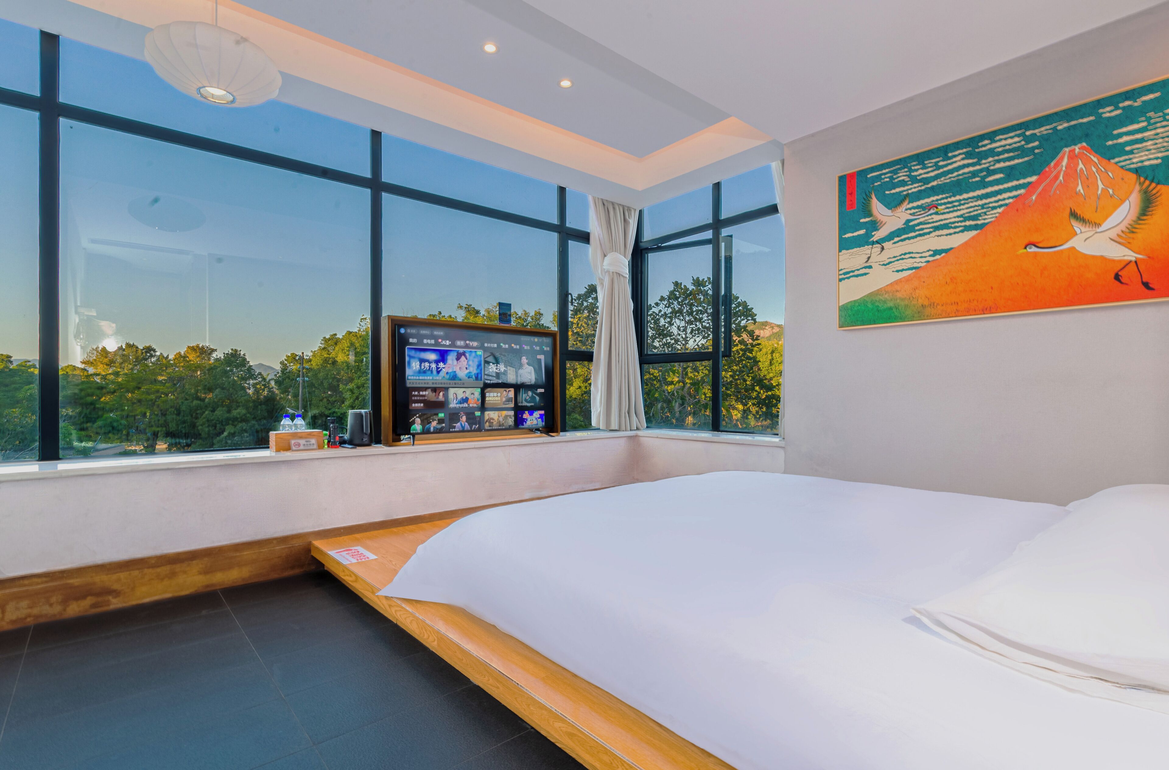 Una camera d'albergo moderna con un letto grande, una TV sul davanzale e un quadro appeso al muro.