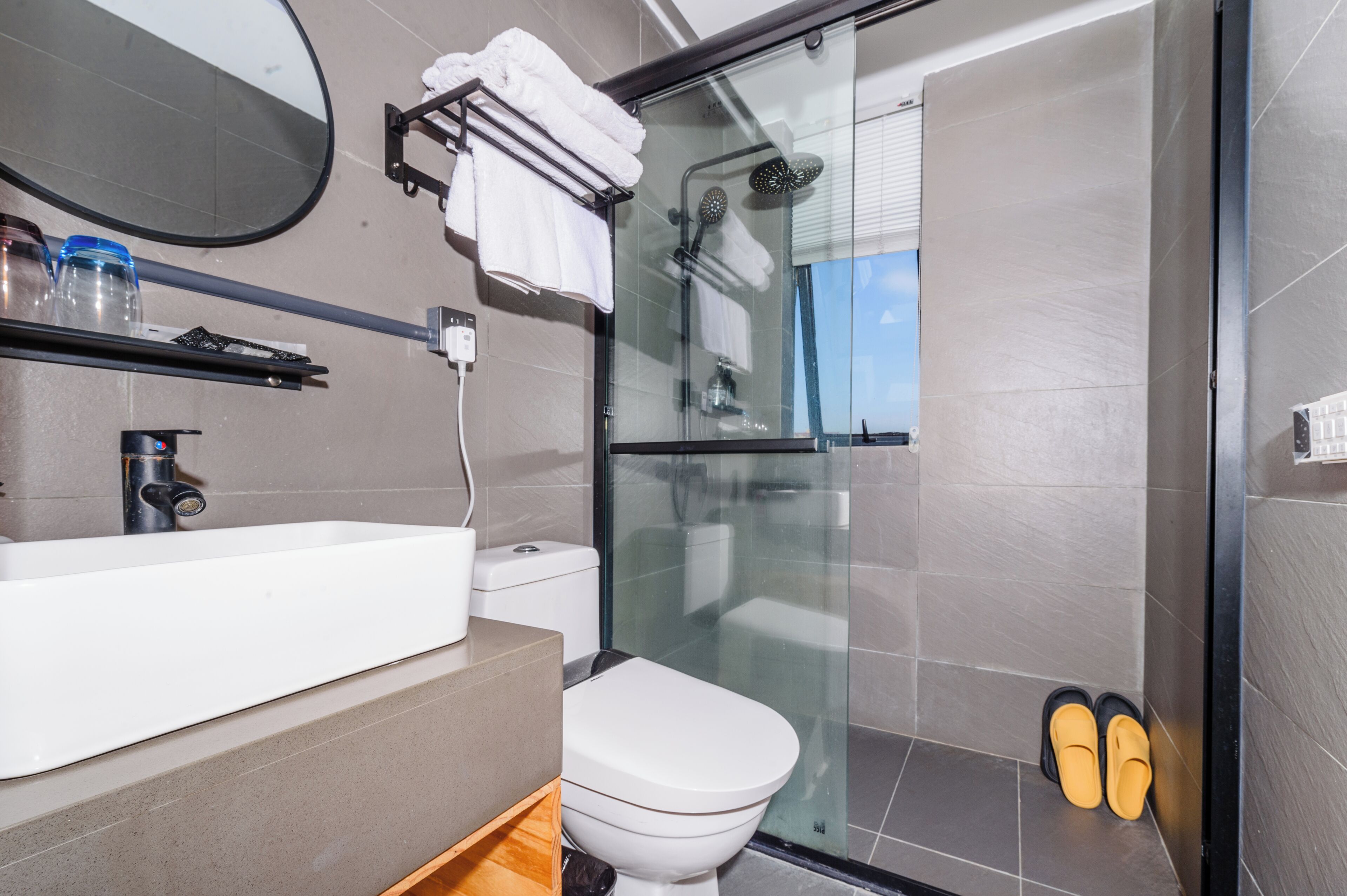 Un baño moderno con ducha de vidrio, lavamanos blanco y un inodoro.