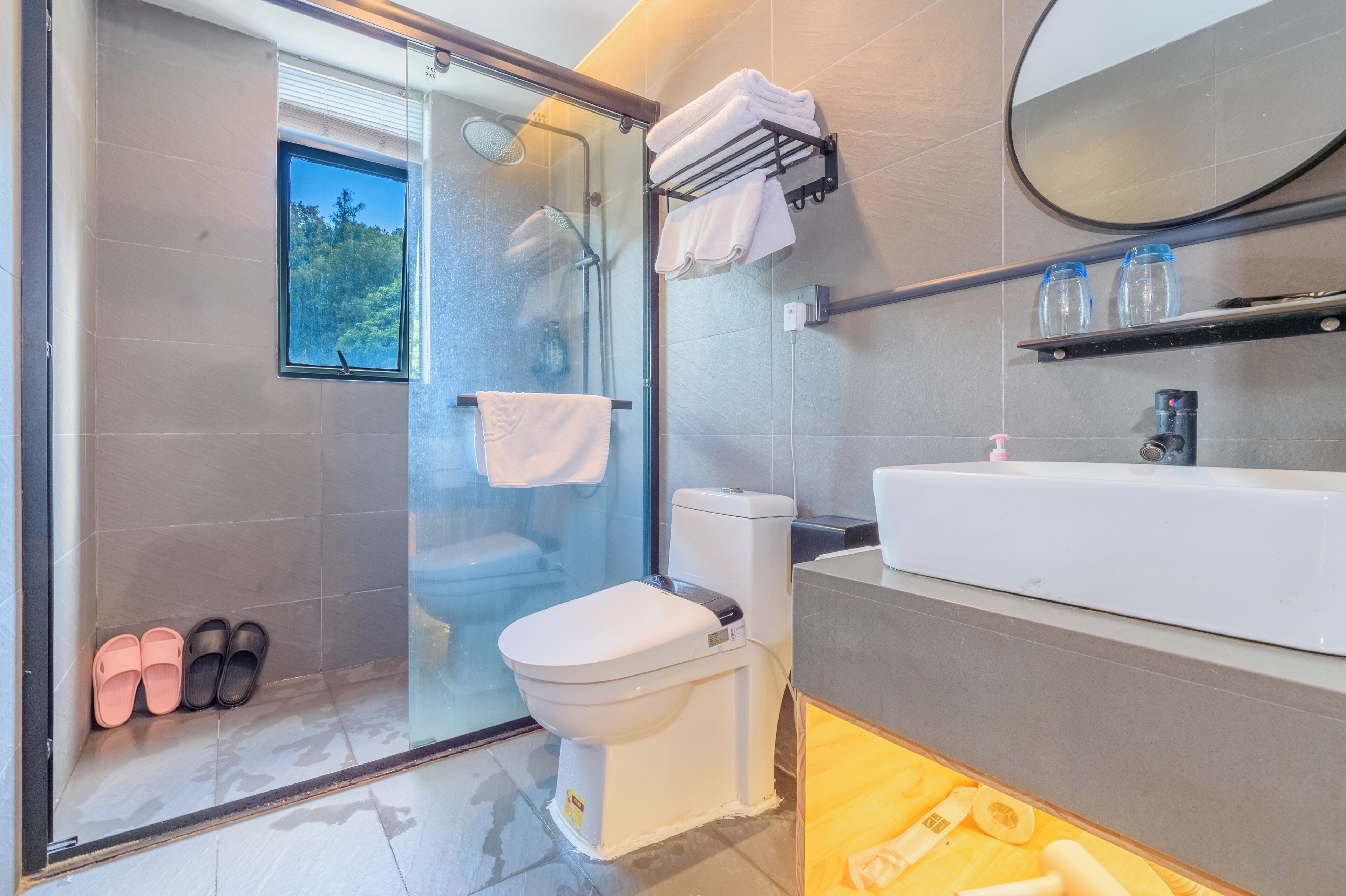 Un baño moderno con cabina de ducha de vidrio, inodoro, lavabo y espejo.
