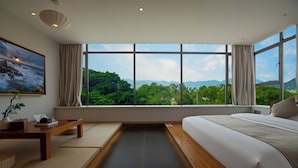A modern bedroom with a large window, a bed, a bedside table, and a view of greenery. - Shenzhen Yusu Linting Inn (Shenzhen)