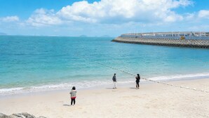 A beach with a rocky breakwater, calm sea, and clear skies. - Shenzhen Yusu Linting Inn (Shenzhen)