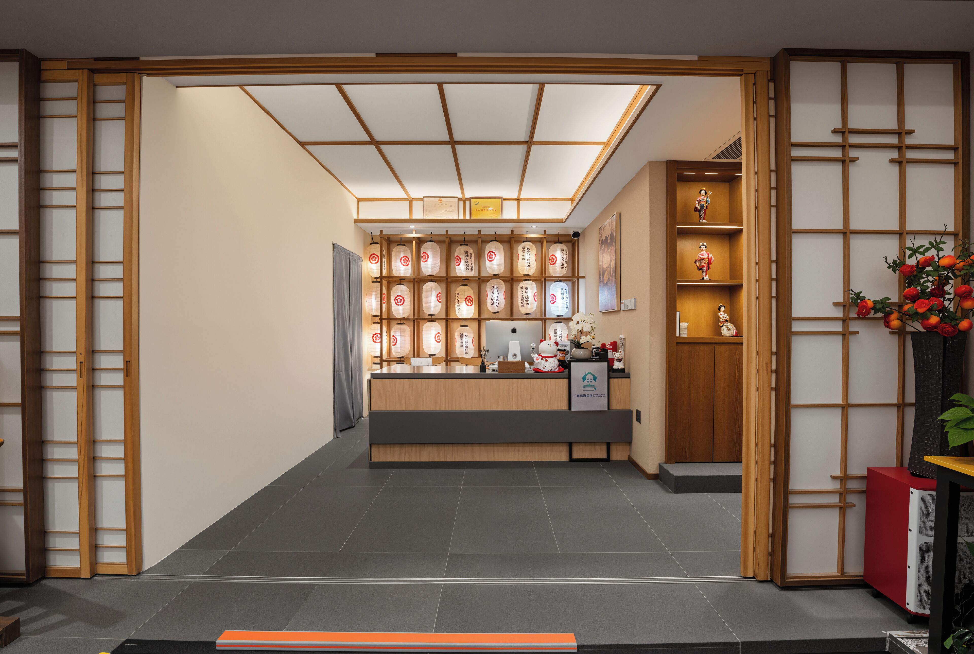 Una recepción con un mostrador de madera, una exhibición de objetos decorativos y una puerta corredera tradicional japonesa.