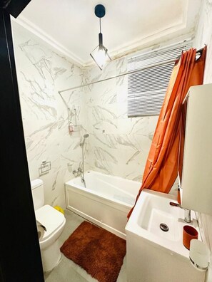 Une salle de bain avec une baignoire, des toilettes et une douche.