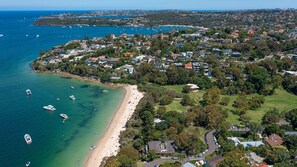 An aerial view of a coastal residential area with a beach, boats, and houses.