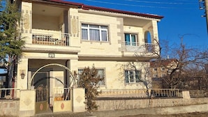 A two-story building with a balcony on the upper floor, a gated entrance, and a clear blue sky. - Hibe Dede Hotel Cappadocia (Nevşehir)