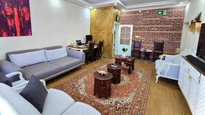 A modern living room with a grey sofa, a white armchair, a coffee table, and a patterned rug. - Hibe Dede Hotel Cappadocia (Nevşehir)