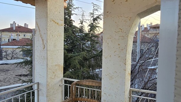 A balcony with a glass table and wicker chairs, overlooking a residential area with trees and buildings. - Hibe Dede Hotel Cappadocia (Nevşehir)