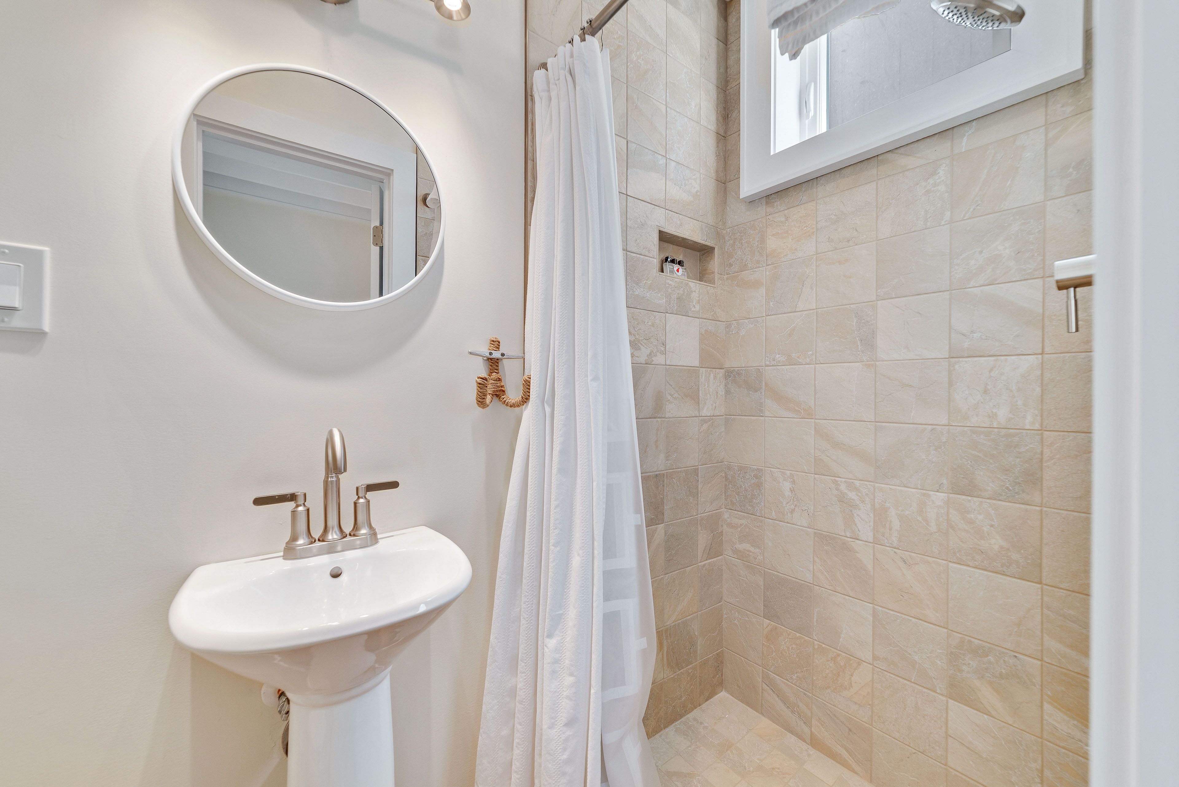 A bathroom with a white sink, a round mirror, and a shower curtain.