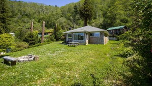 Un piccolo chalet con veranda e tavolo da picnic in una zona boscosa.