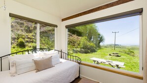 Una camera da letto con un letto, una finestra vista su un prato e un tavolo da picnic.