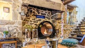 A stone fireplace with a blue sign reading "SANT-STEN" and a metal pot on a wooden table. - Maison du Bosco by Interhome (Auray)