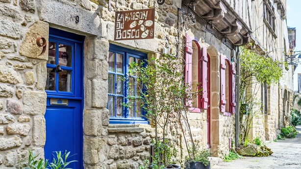 A stone building with a blue door and windows, potted plants outside, and a sign above the door. - Maison du Bosco by Interhome (Auray)