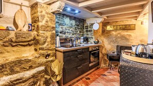 A rustic kitchen with stone walls, wooden cabinets, and a tiled floor. - Maison du Bosco by Interhome (Auray)