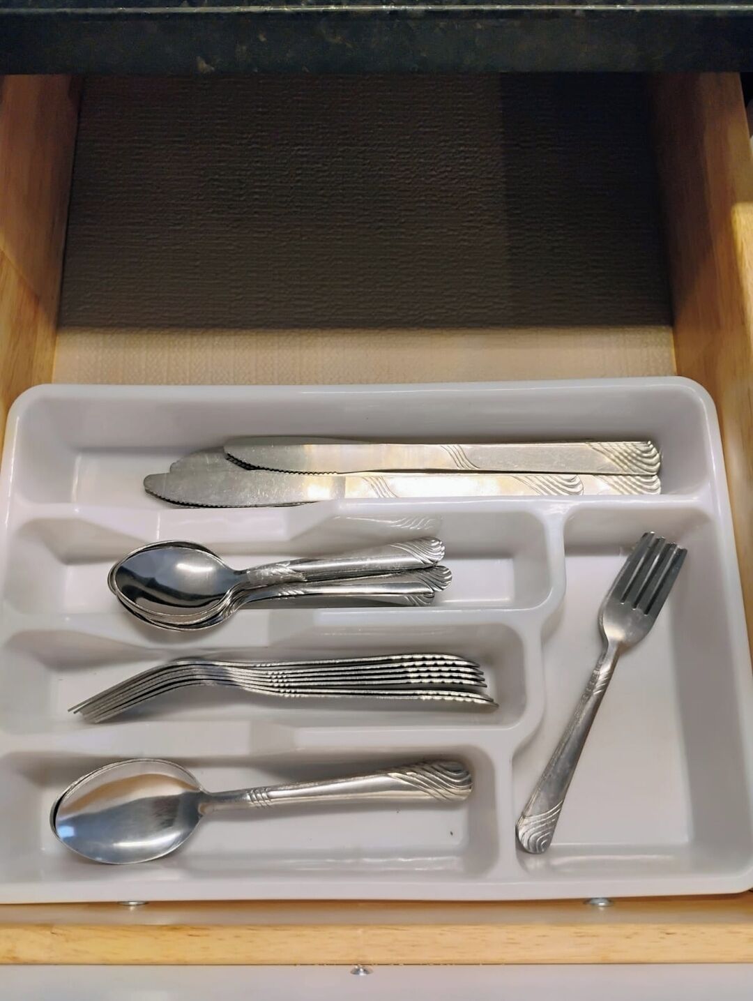 Un cajón con cubiertos, incluyendo un tenedor, cuchillo, cuchara y otro tenedor.