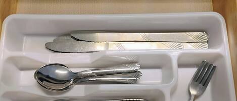 Un cajón con cubiertos, incluyendo un tenedor, cuchillo, cuchara y otro tenedor.