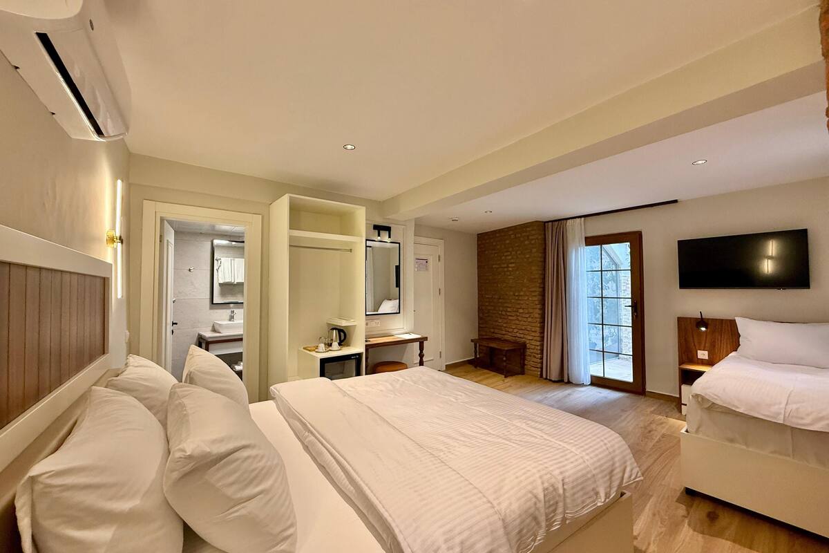 A hotel room with two beds, a bathroom, a desk, and a TV.