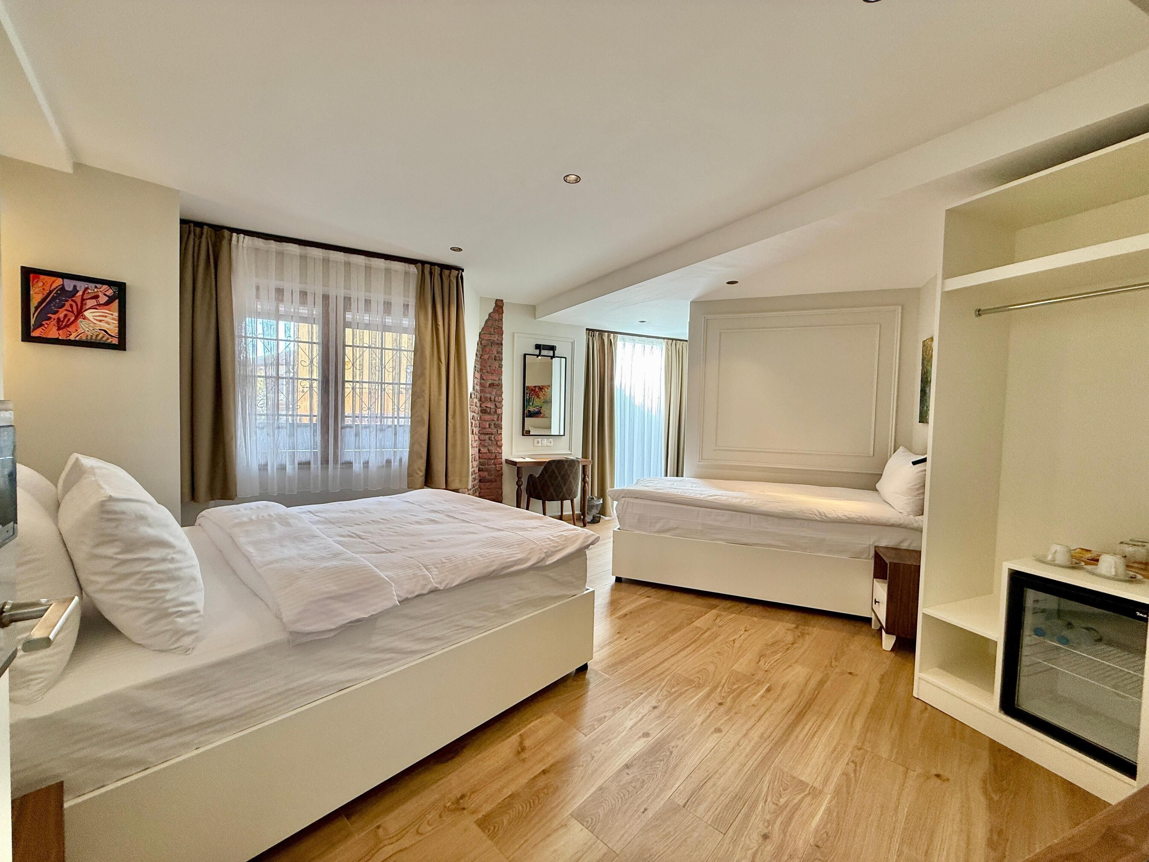 Habitación de hotel con dos camas, un escritorio, una silla y un armario.