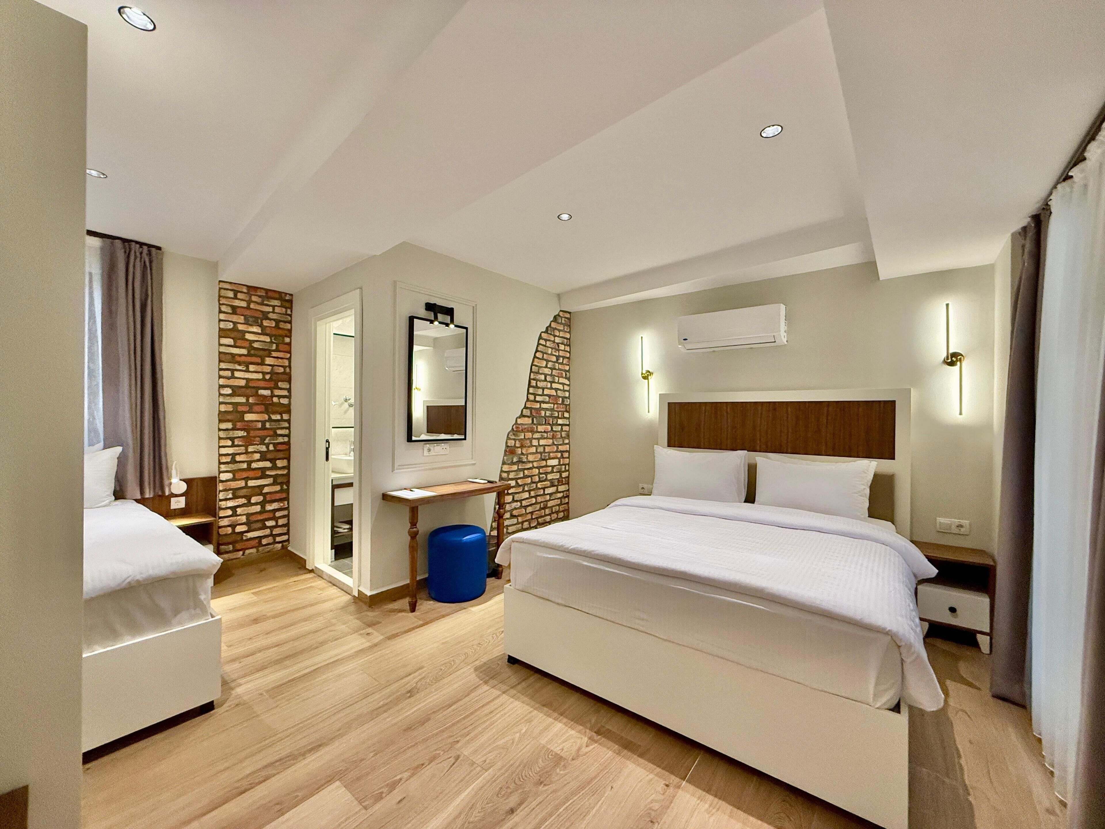 A modern hotel room with a large bed, a desk, and a bathroom visible through an open door.