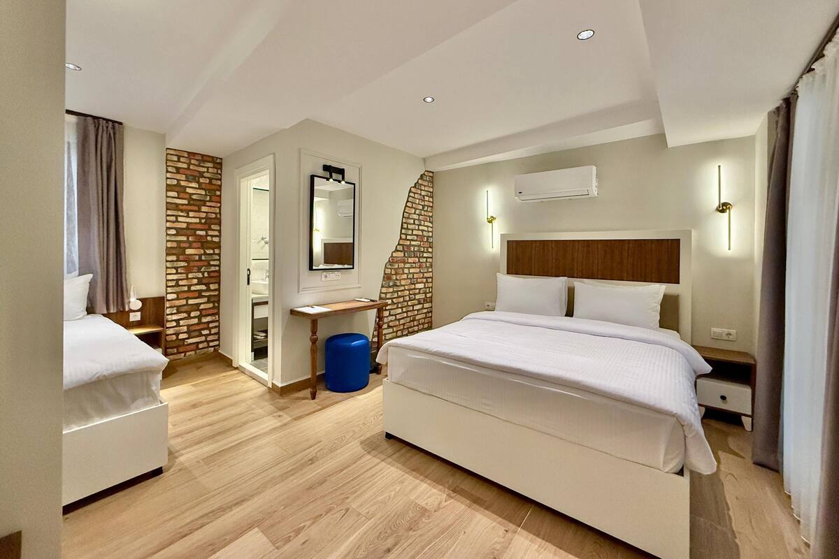 A modern hotel room with a large bed, a desk, and a bathroom visible through an open door.