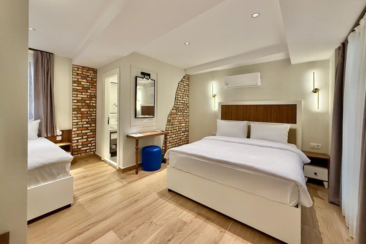 A modern hotel room with a large bed, a desk, and a bathroom visible through an open door.
