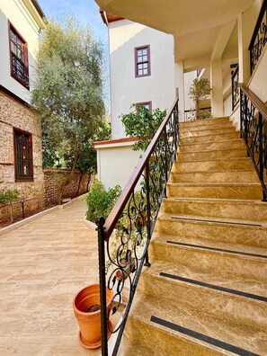 A staircase with a wrought iron railing leading to a building with a stone facade and a white exterior.