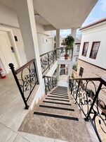 A multi-level residential building with a marble staircase, metal railings, and a potted plant on the balcony.