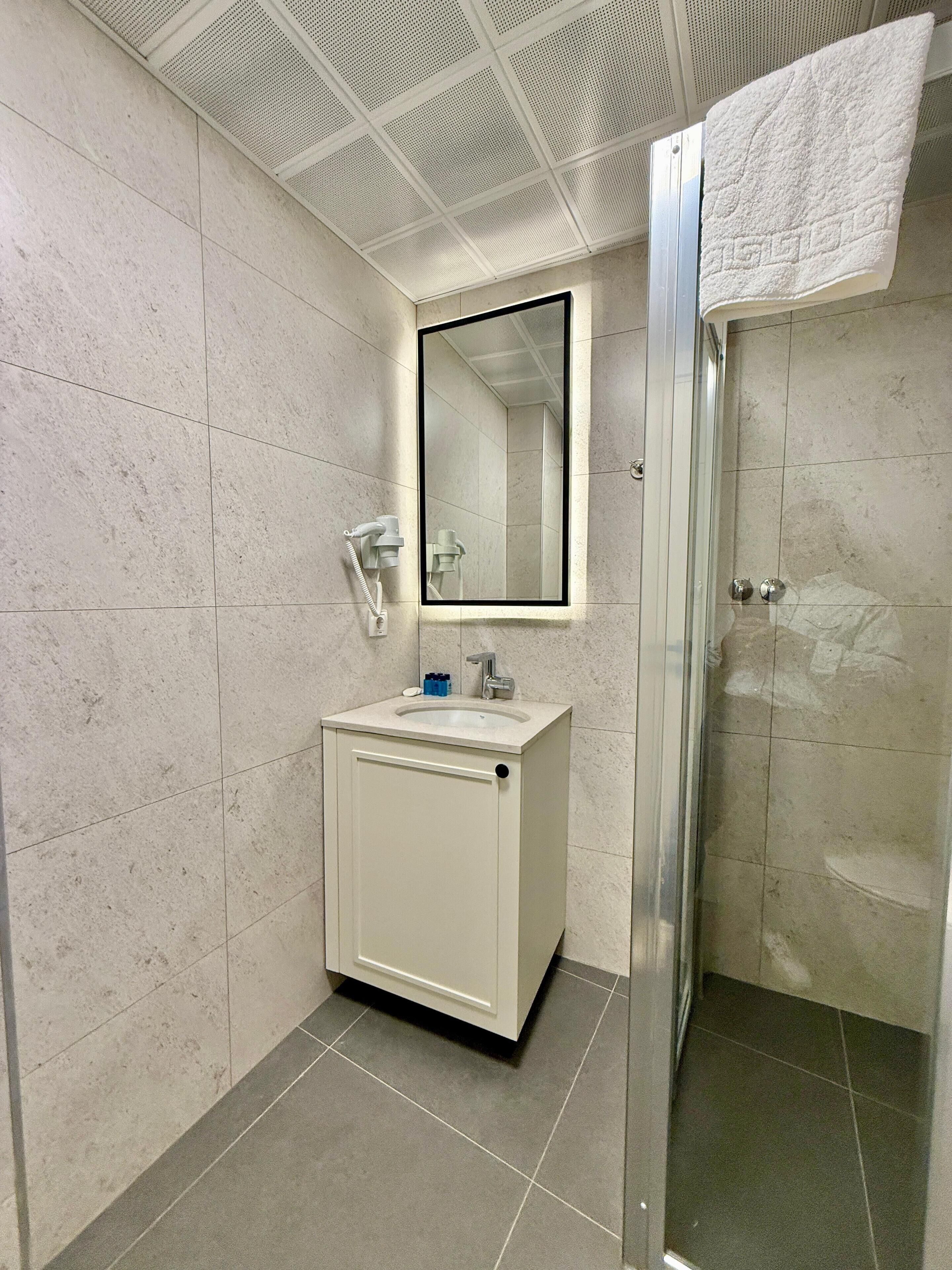 A bathroom with a white sink, a mirror, and a shower.