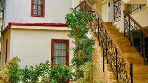 A multi-story building with a staircase, potted plants, and a tiled courtyard. - Adria Inn (Antalya)
