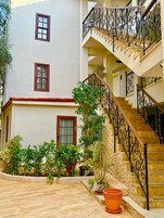A multi-story building with a staircase, potted plants, and a tiled courtyard.