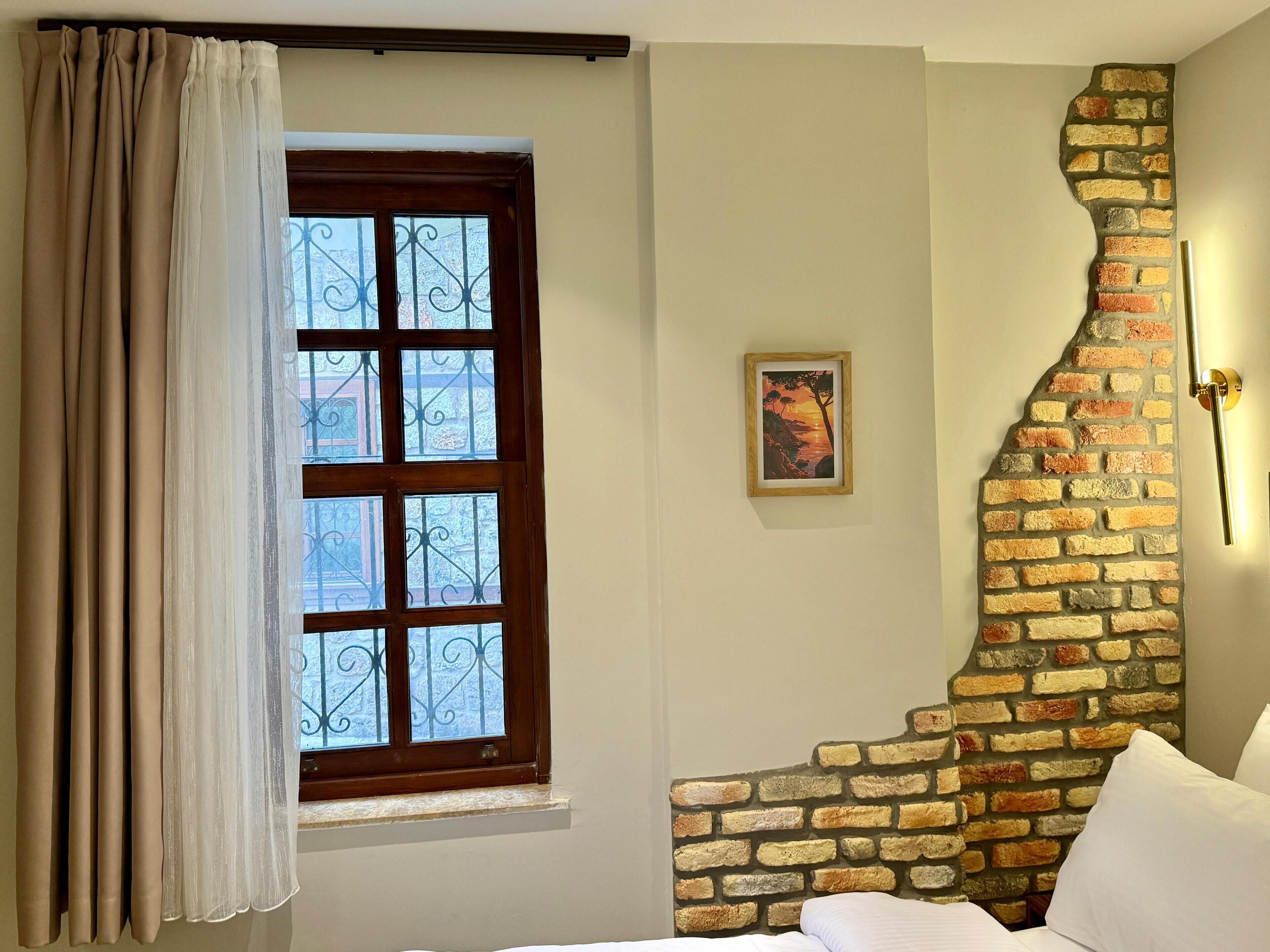 A room with a large window, a brick wall accent, and a framed picture on the wall.