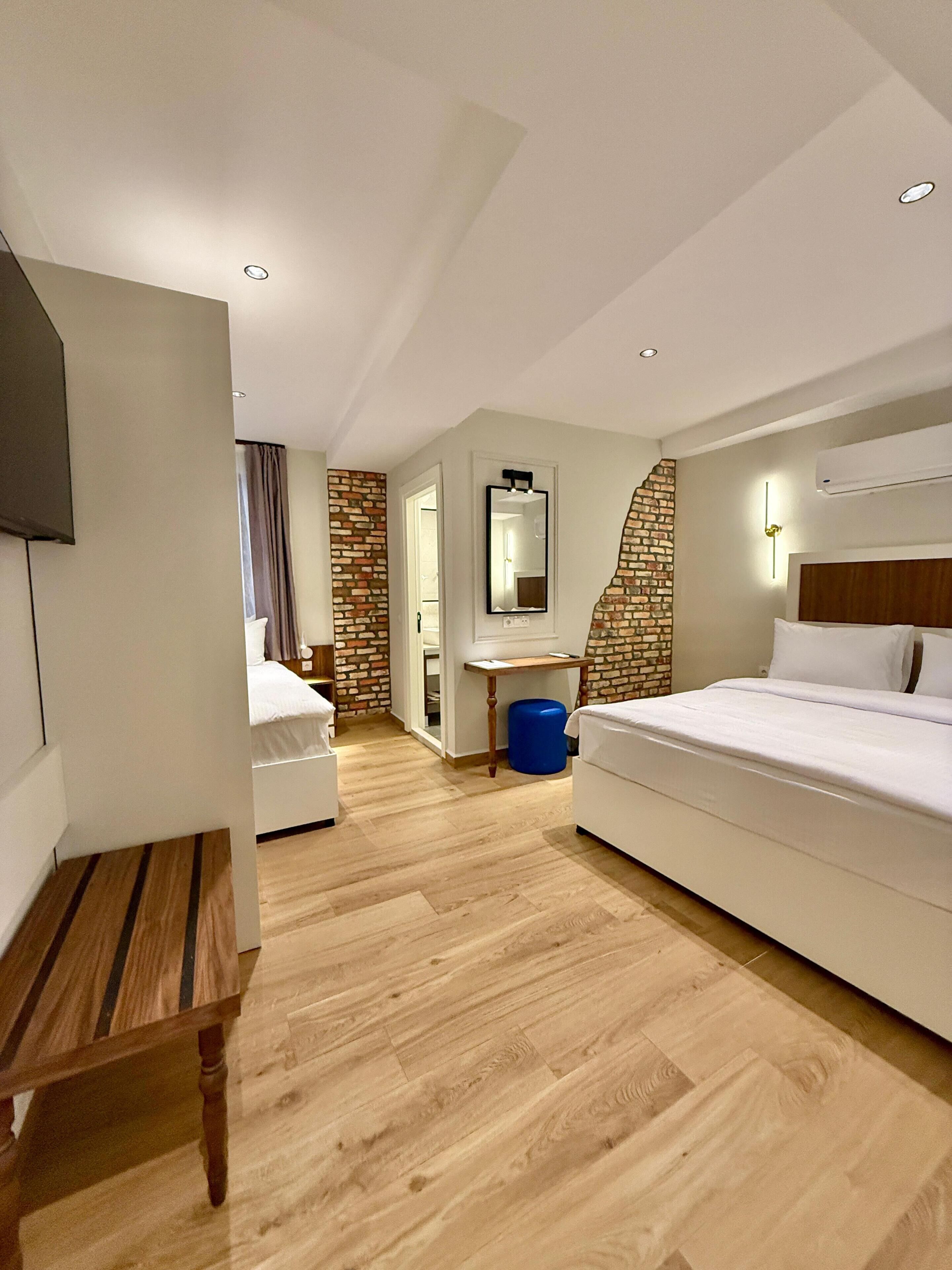 A hotel room with a bed, a desk, a mirror, and a television.