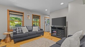 Ein modernes Wohnzimmer mit grauem Sofa, einem Fernsehschrank und einem Kamin.