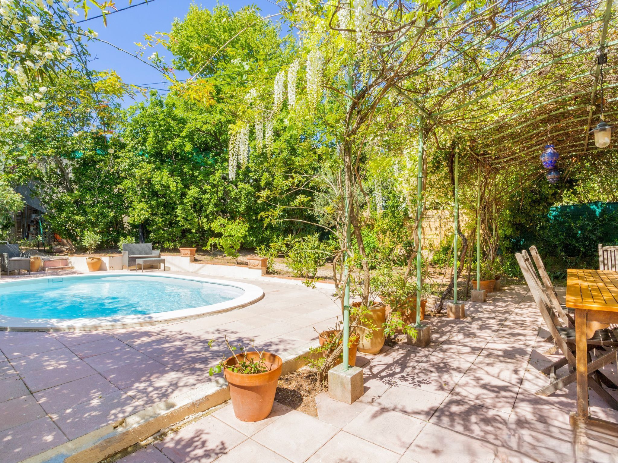 Un espace piscine doté d’une piscine circulaire, de sièges disposés tout autour et de plantes en pot.