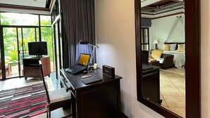 A hotel room with a large mirror, a desk with a laptop, a television, and a view of the outdoors. - Lilac 1 Bedroom Private Pool Villa Rawai (Rawai)