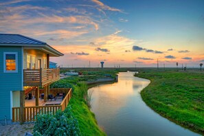 Ein Haus mit Balkon, das auf einen Kanal mit viel Grünblick bietet.