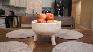 A kitchen with a wooden table, a bowl of fruit, and a brick backsplash. - Stunning Pet Friendly House with King Bed and Texas Size Backyard in Weslaco (Weslaco)