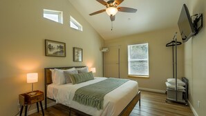 A bedroom with a bed, bedside lamps, a ceiling fan, a window, and a wall-mounted TV. - New 1 Bed Near Yosemite, Fire Pit, Washer, Dryer (Mariposa)